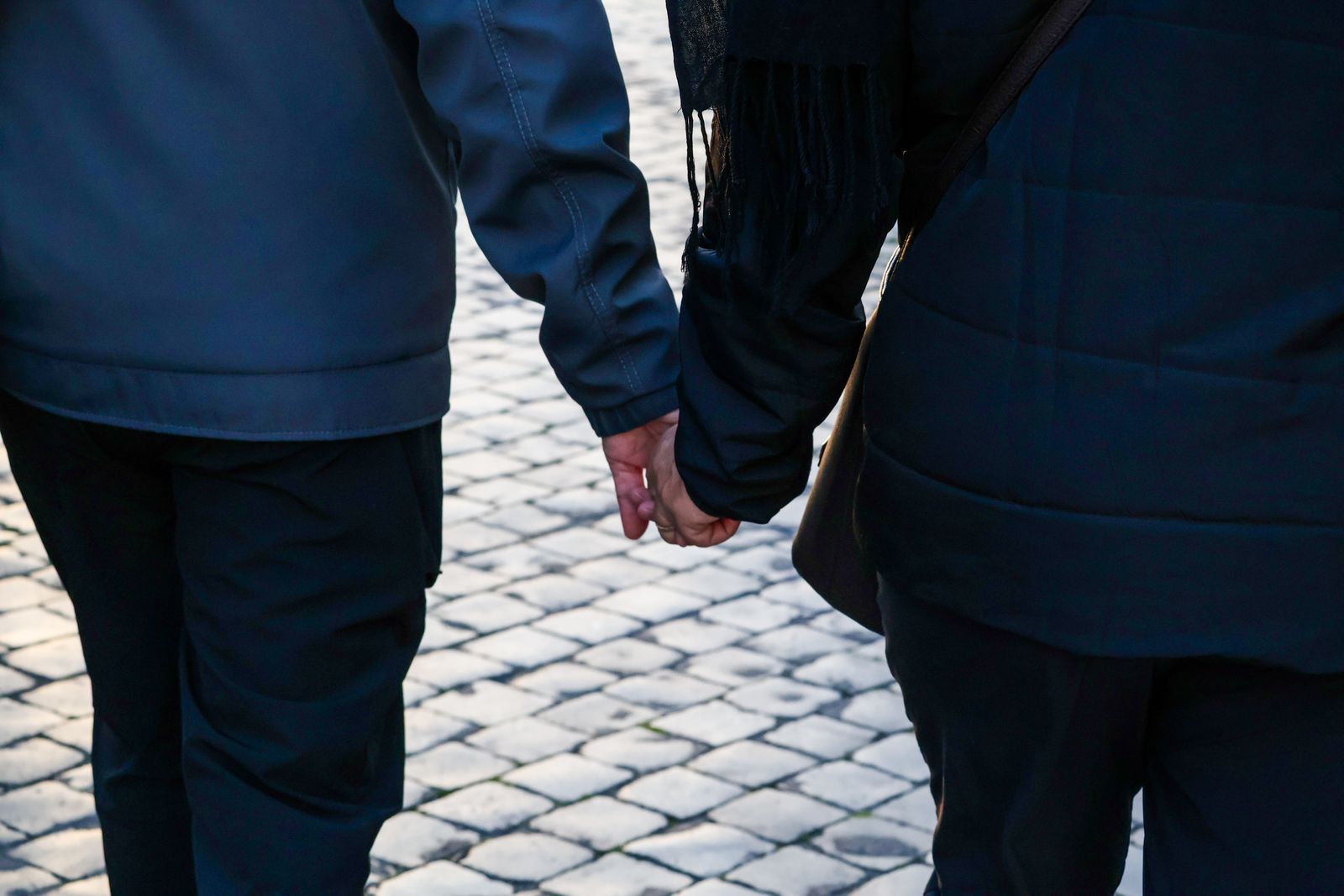 Couple holding hands while walking along a cobblestone street