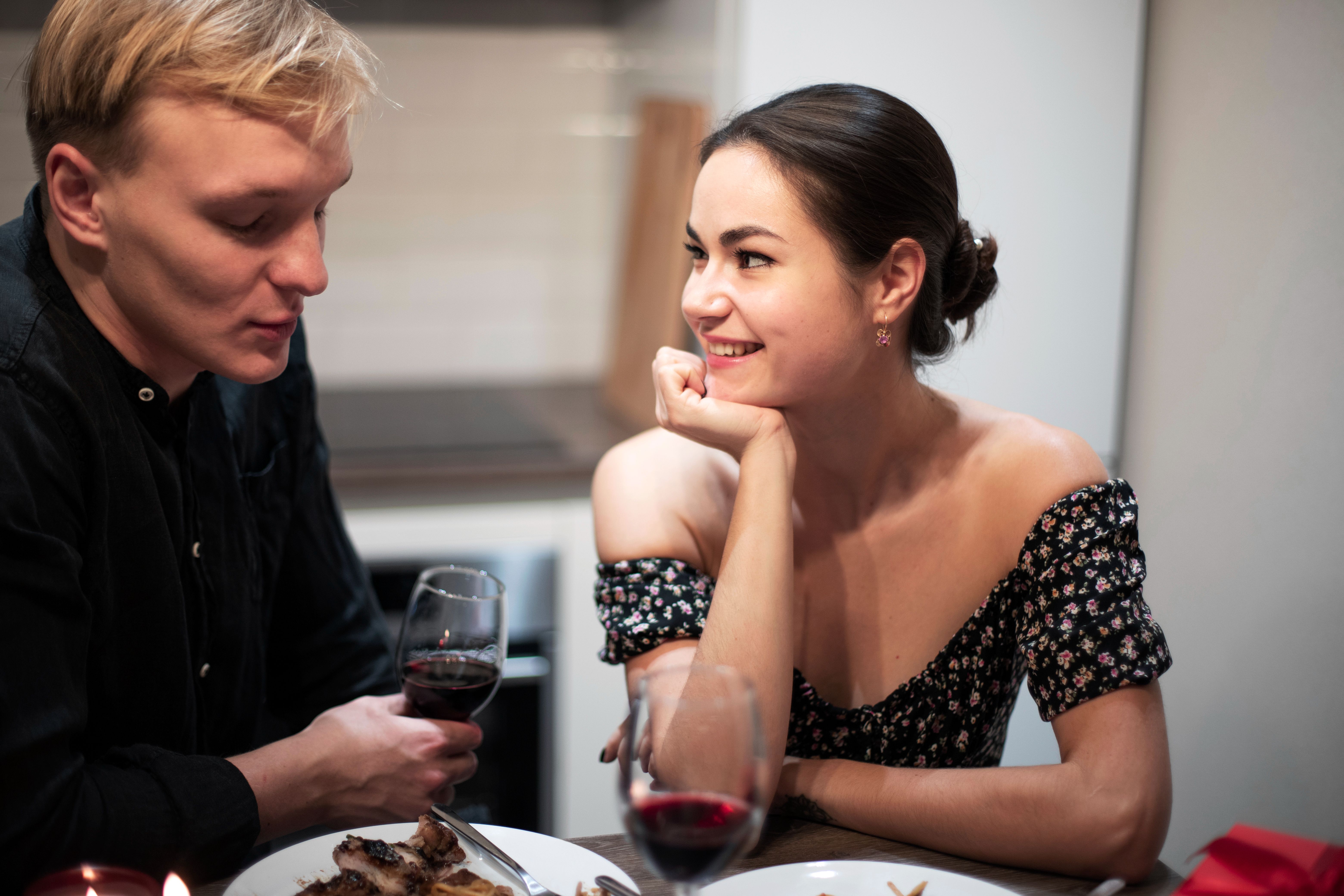 Young couple sharing eye contact and smiling during an intimate Valentine's Day dinner date.