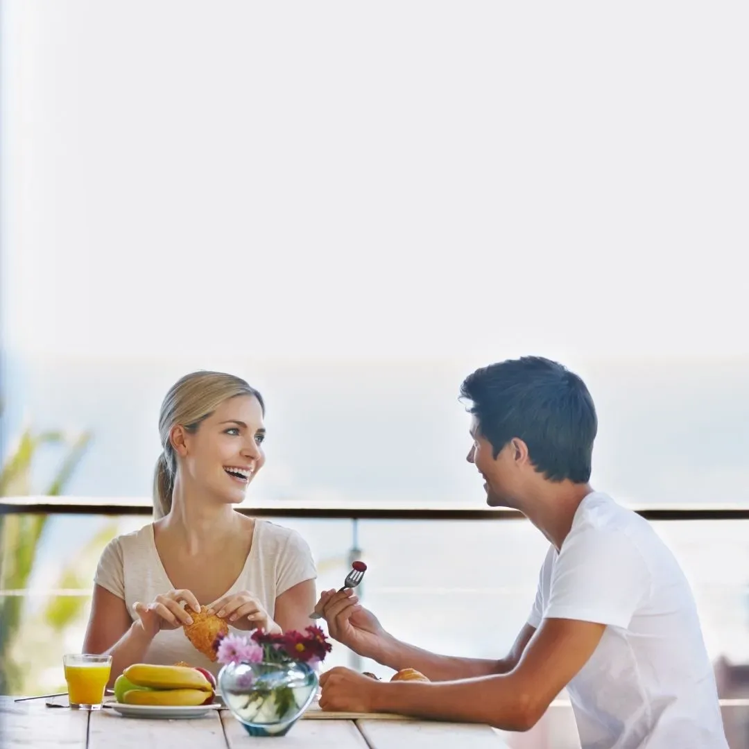 Couple smiling over breakfast at a table, representing a healthy relationship and everyday support during academic goals.