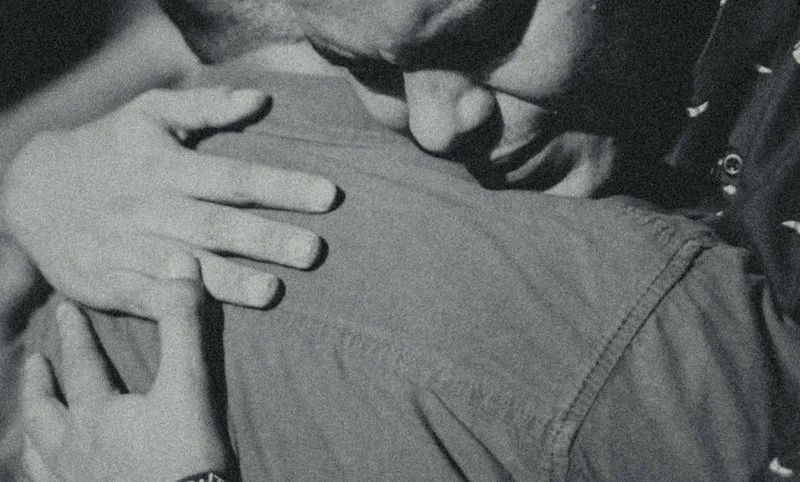 Black and white close-up of two people hugging tightly in an intimate emotional embrace