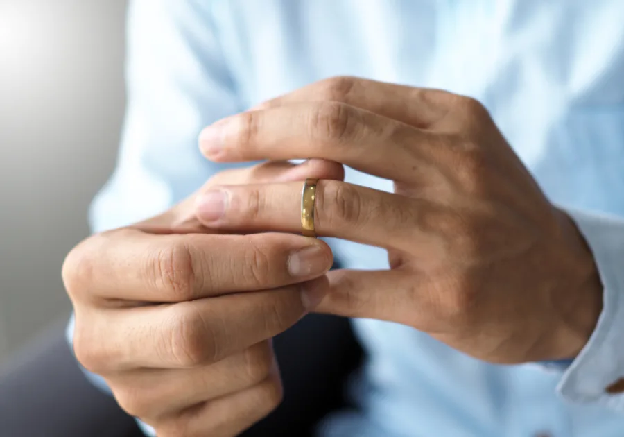 Close-up of hands adjusting a gold wedding ring, symbolizing marriage, commitment, and strain in a romantic relationship.