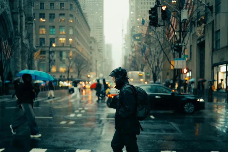 Person walking through a rainy city intersection, symbolizing loneliness, resilience, and entering a new year with emotional honesty.