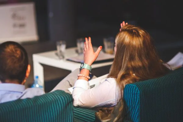 Woman raising her hand while seated in discussion, representing communication, emotional honesty, and relationship growth.
