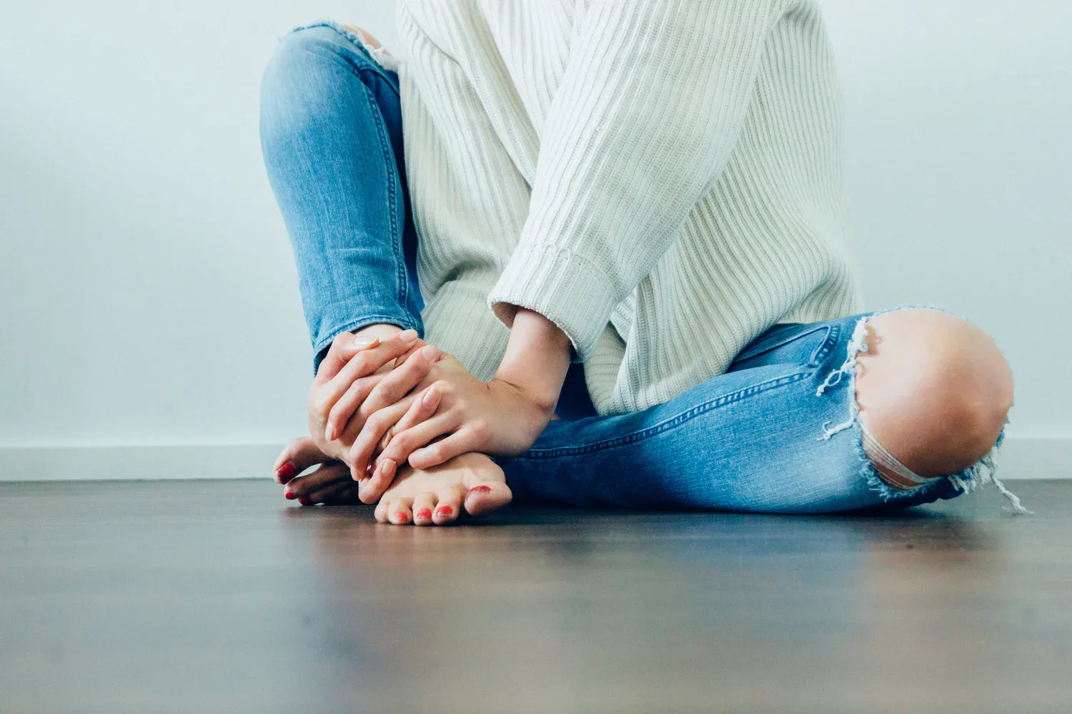 Person sitting on the floor with knees drawn in, symbolizing reflection, vulnerability, and emotional reset before the new year.