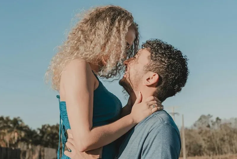 Happy couple embracing outdoors under a blue sky, symbolizing romance, growth, and celebrating graduation together.