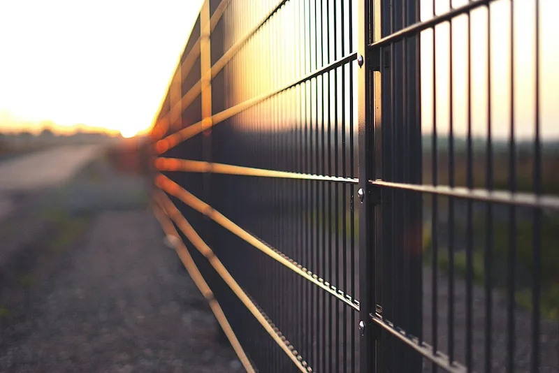 Close-up of a metal fence at sunset representing personal boundaries, protection, and healthier relationships in the new year.