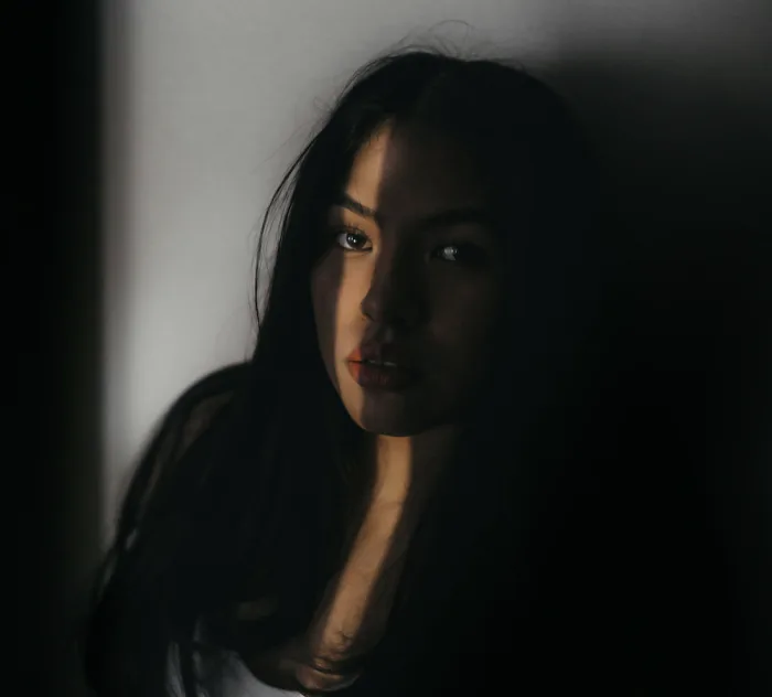 Moody portrait of a woman in shadow with a reflective, serious expression