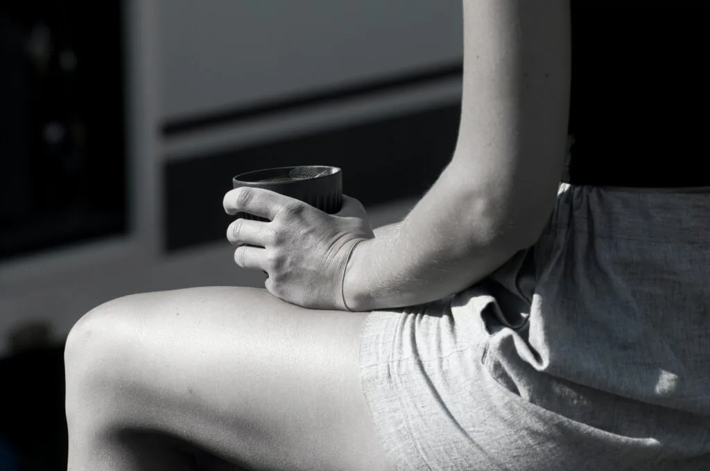 Close-up of a seated woman holding a cup in soft light, representing reflection, vulnerability, and emotional intimacy before commitment.