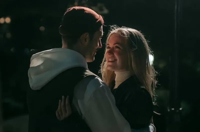Young couple at night smiling into each other's eyes, symbolizing support, admiration, and romantic connection after graduation.