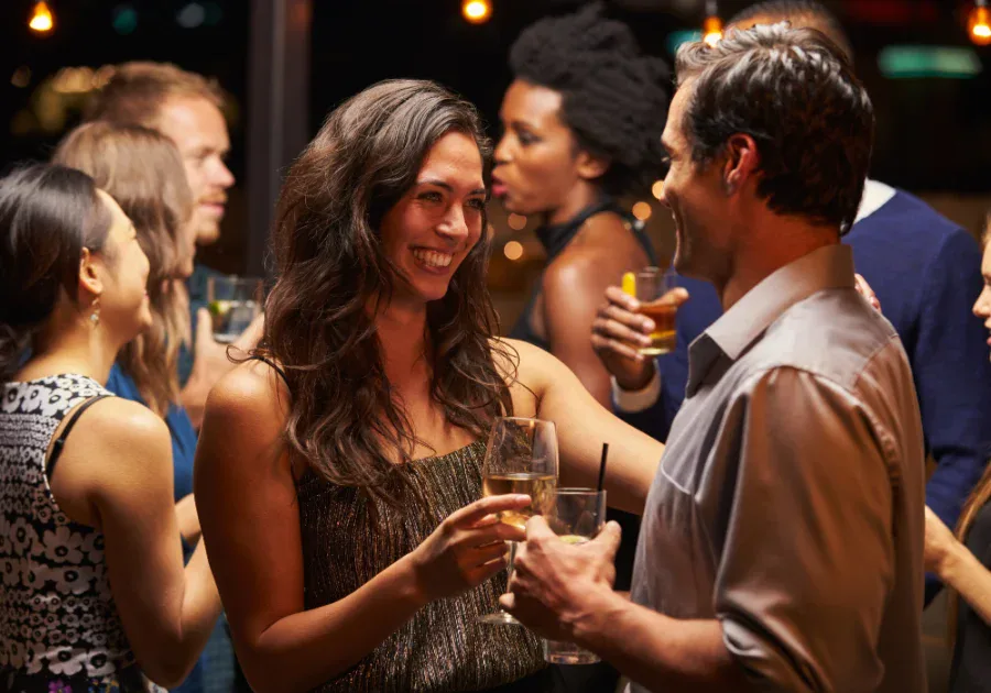 Woman smiling warmly at a man during a social gathering, representing attraction, confidence, and the start of a new chapter.