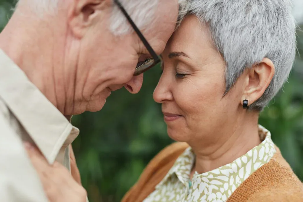 Mature couple touching foreheads gently, expressing trust, emotional attunement, and lasting intimacy.